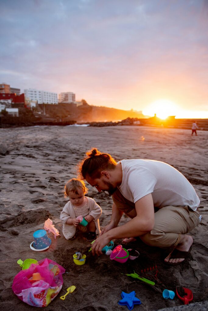 pexels-photo-3968119-3968119 A dad and child enjoy playful bonding at a beach during a vibrant sunset.